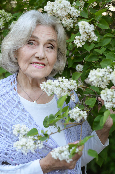  senior beautiful woman posing with white  lilacs in   park - Foto, Imagem