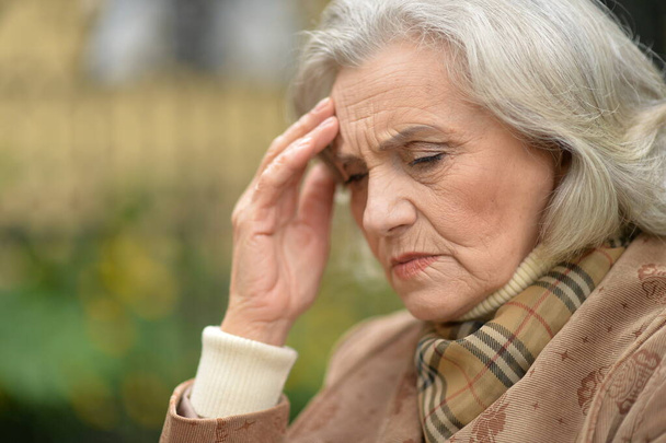 senior woman suffering from headache  in  park - Fotoğraf, Görsel