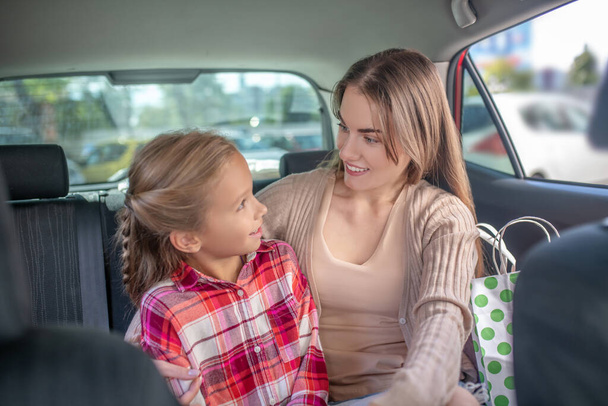 Happy mom and daughter hugging on car backseat - Photo, image