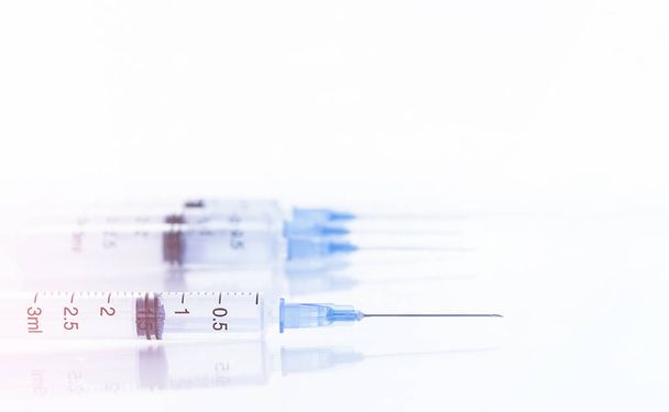 four syringes lie on a white glass table - Fotó, kép