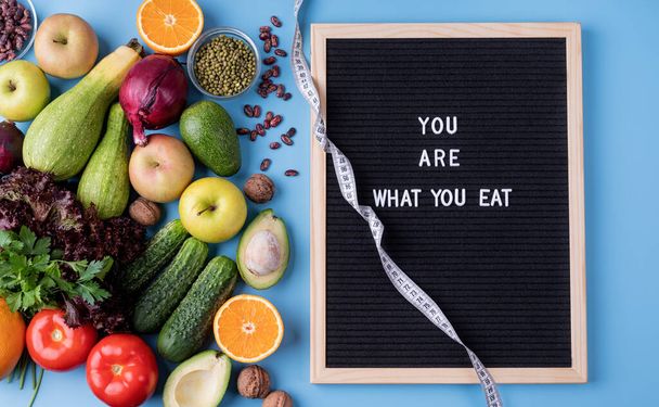 Fresh vegetables and fruit for healthy diet, measuring tape and black letter board with words You Are What You Eat top view flat lay with copy space - Fotoğraf, Görsel
