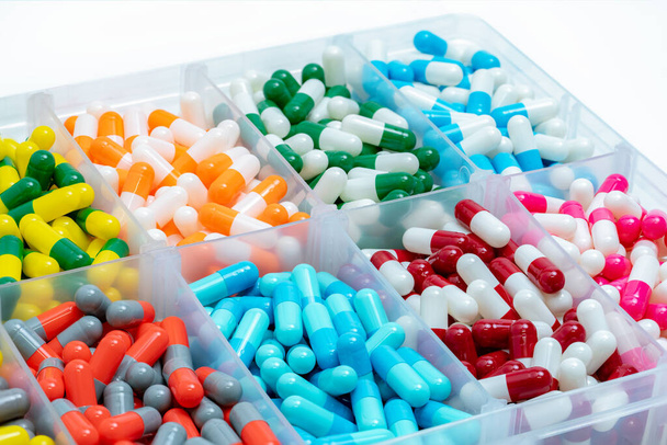 Colorful capsules pill in plastic box.  Pharmaceutical industry. Pharmacy drugstore products. Drug interactions. Healthcare and medicine background. Bright color of capsules pills in plastic tray. - Photo, Image