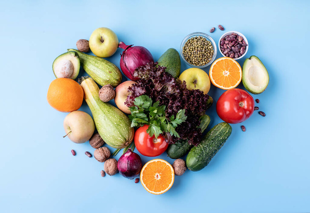 φρέσκα φρούτα και λαχανικά σε σχήμα καρδιάς πάνω όψη επίπεδη θέσει σε μπλε φόντο - Φωτογραφία, εικόνα