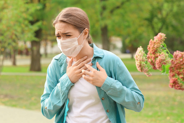 Young woman in medical mask suffering from pollen allergy outdoors - Photo, Image