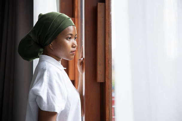 Üzgün Afrikalı genç kadın kanser hastasının portresi hastalıkla mücadele ediyor, kemoterapi, kanser farkındalığı gibi ciddi saç dökülmesi yan etkilerinden sonra başörtüsü takıyor. - Fotoğraf, Görsel