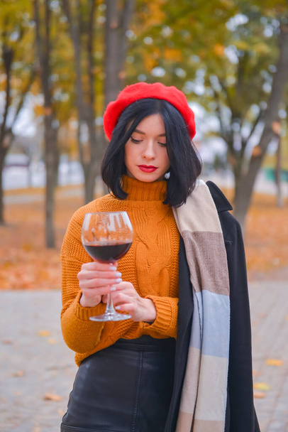 Portrait of a gorgeous young brunette woman having wine fun. Girl in autumn clothes with a glass of wine outside during fall season. Banner, drinking wine concept. - Photo, image