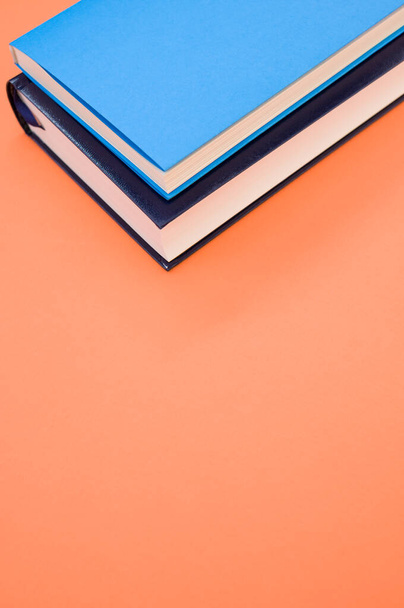 A closeup of the hardcover books on the orange surface - space for text - Photo, image