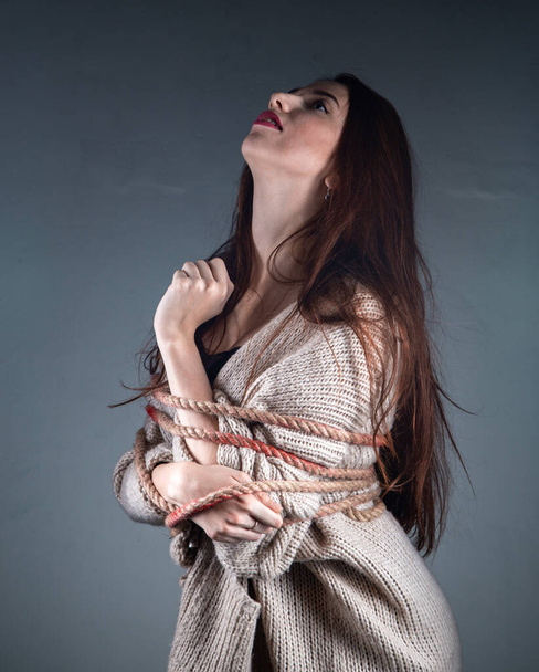 Fénykép fiatal kötött lány kötéllel pulóver szürke háttér - Fotó, kép