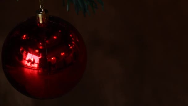 Koncepční video blikajících světel odrážejících se na červeném vánočním ozdobě na tmavém pozadí - Záběry, video