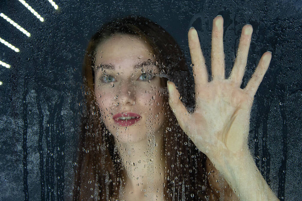 Капля молодой девушки, касающейся стекла каплями воды - Фото, изображение