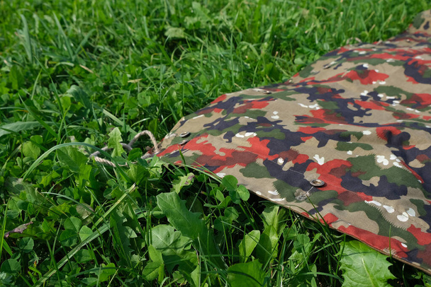 A closeup shot of a camouflage waterproof blanket on a fresh cultivated lawn - Fotografie, Obrázek