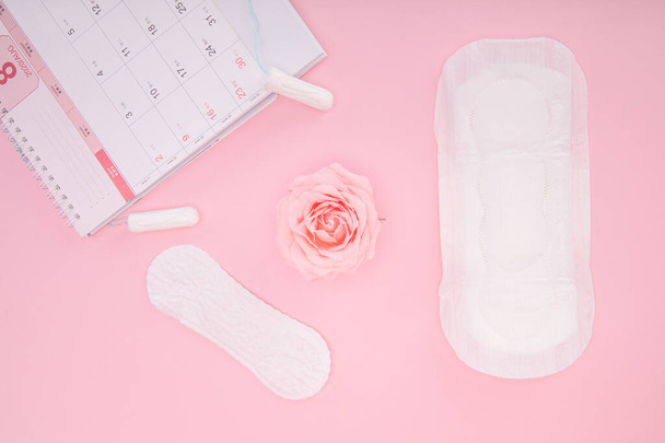 Un calendario di periodo, assorbenti igienici e assorbenti su sfondo rosa - Foto, immagini