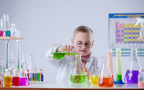 Funny young chemist pouring reagent into flask - Foto, afbeelding