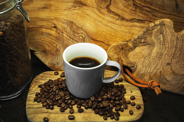 A high angle shot of a cup of coffee and coffee beans on a wooden surface - Foto, afbeelding