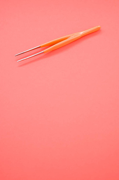 A vertical shot of an orange hair tweezer on red background with a copy space - 写真・画像