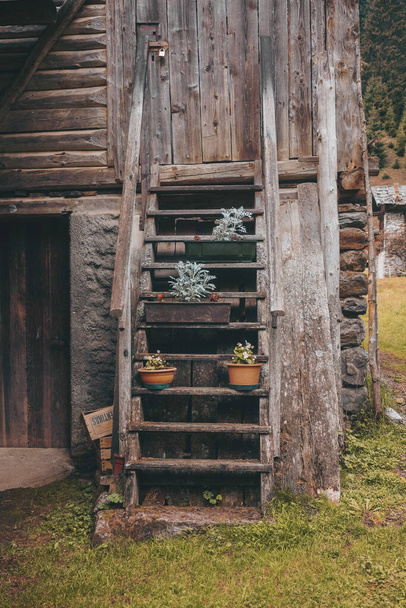 A vertical shot of a wooden log cabin staircase decorated with flowerpots - Fotoğraf, Görsel