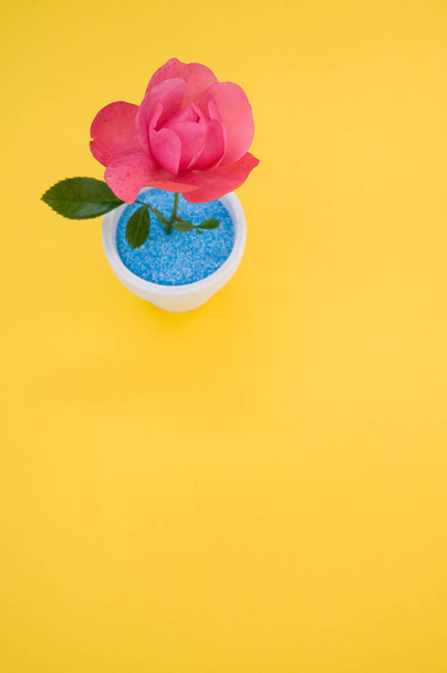 A top view of a decorative artificial pink rose in a pot on the yellow surface - space for text - Foto, immagini
