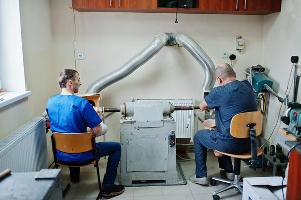 Két protézis férfi munkás, akik műlábat készítenek, miközben laborban dolgoznak.. - Fotó, kép