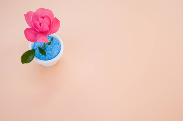 A top view of a decorative artificial pink rose in a pot on the orange surface - space for text - Foto, afbeelding