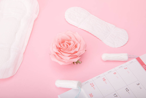 A period calendar, sanitary pads and tampons on a pink background - Fotografie, Obrázek