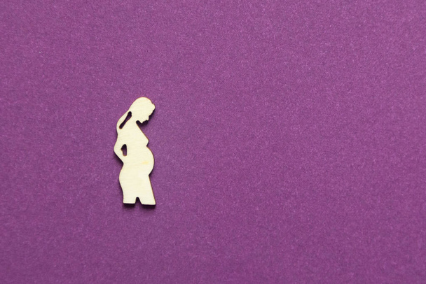 Silhouette of a figure of a pregnant woman on a purple background. - Foto, imagen