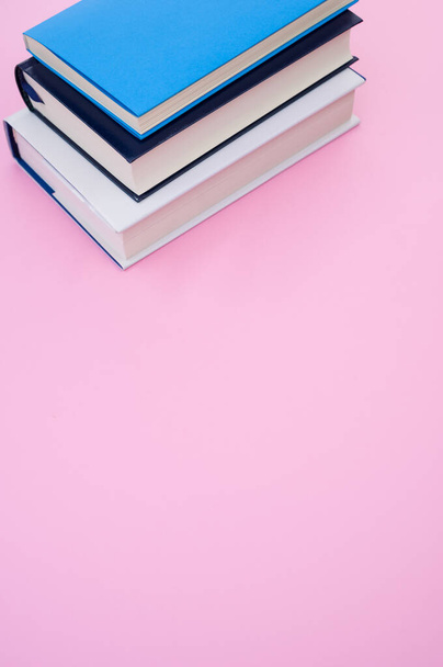 A closeup of the hardcover books on the pink surface - space for text - Фото, изображение