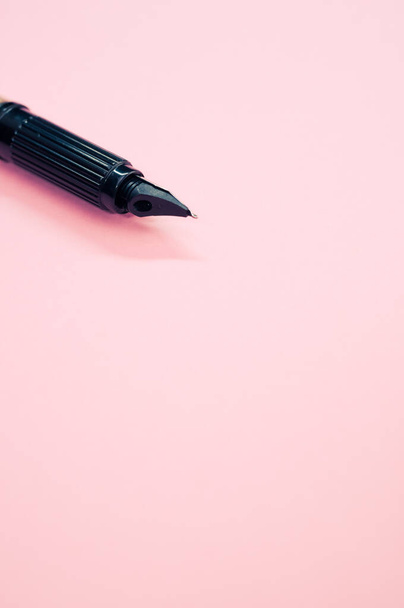 A vertical closeup of a fountain pen on pastel pink background with a copy space - Zdjęcie, obraz