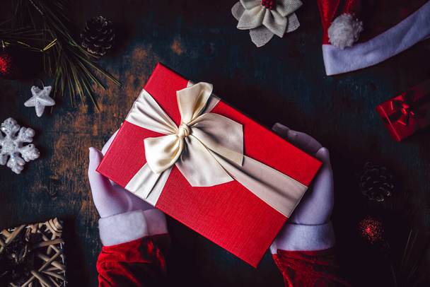A closeup shot of hands wearing white gloves holding a Christmas present - Foto, afbeelding