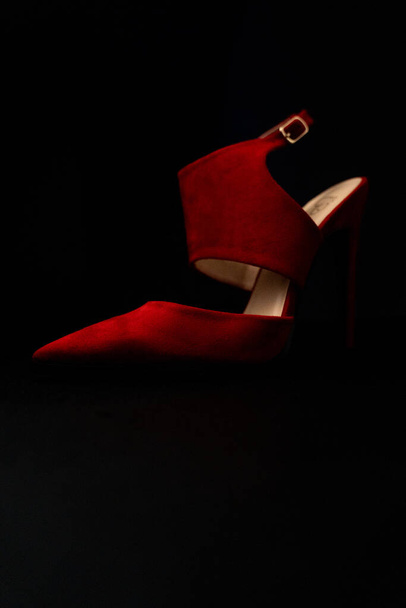 A vertical shot of red high-heeled shoe isolated on a black background - Foto, imagen