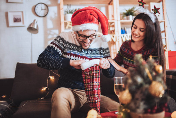 Cheerful man and woman opens Christmas gift at home. - Fotografie, Obrázek