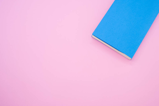 ピンクの表面に青いハードカバーの本のトップビュー-テキストのためのスペース - 写真・画像