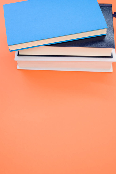 A closeup of the hardcover books on the orange surface - space for text - Foto, Bild