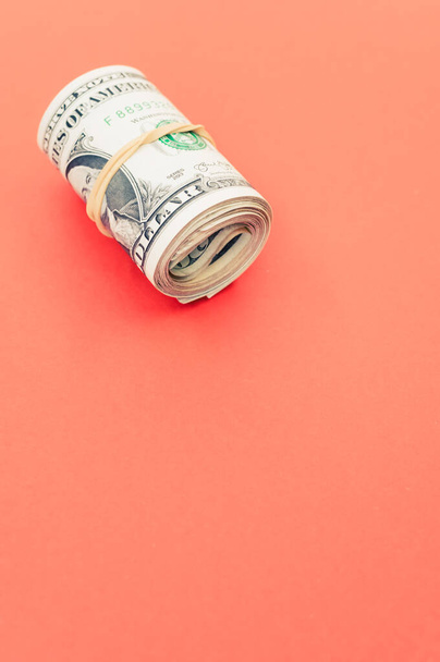 A vertical shot of rolled-up dollar bills on a red surface - Fotoğraf, Görsel