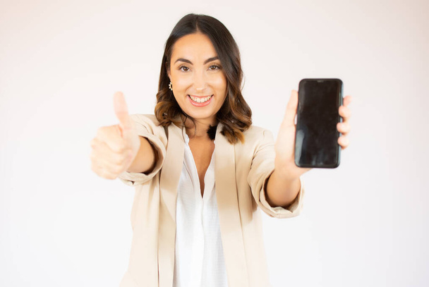 Jonge elegante vrouw met een mobiele telefoon tegen een witte achtergrond - Foto, afbeelding