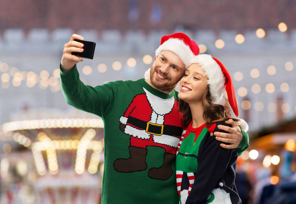 happy couple in christmas sweaters taking selfie - Photo, image