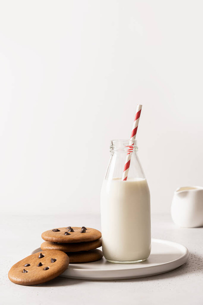 Milch für den Weihnachtsmann in der Flasche mit Stroh und Keksen auf weißem Hintergrund. Nahaufnahme. - Foto, Bild