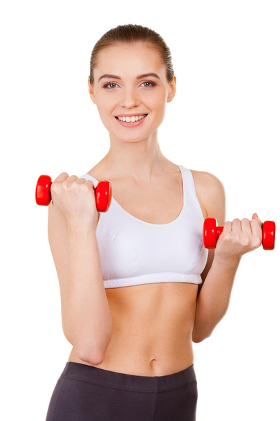 Woman in sports clothing training with dumbbells and smiling - Φωτογραφία, εικόνα