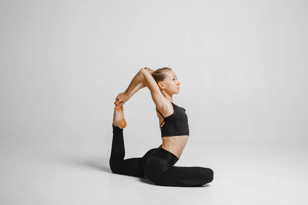 vrouw in zwart bodysuit doen stretching yoga pose - Foto, afbeelding