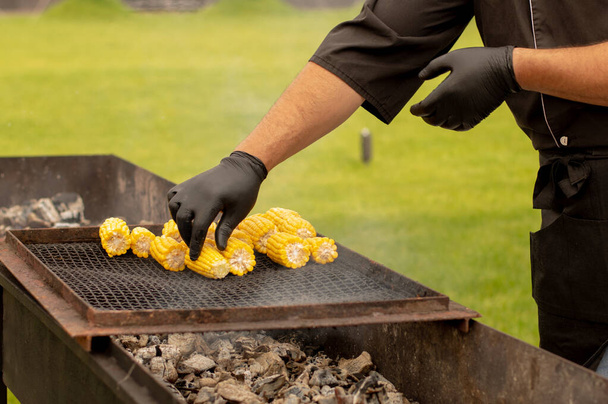 The chef prepares grilled corn on a sunny day. Fast food. - Photo, Image