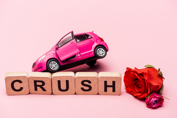 roses, toy car and word crush on cubes on pink background - Photo, Image