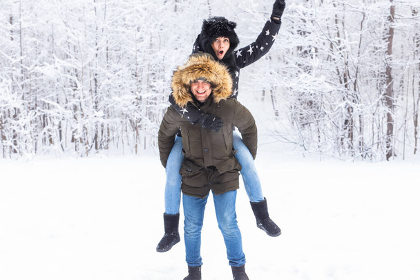 Πορτρέτο του ευτυχισμένου νεαρού ζευγαριού στο χειμερινό πάρκο με το φίλο τους πίσω - Φωτογραφία, εικόνα