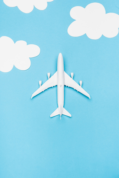 top view of white plane model on blue background with white clouds - Photo, Image