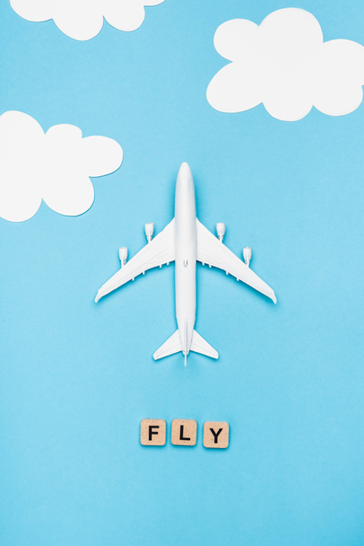 top view of plane model and cubes with word fly on blue sky background - Fotó, kép