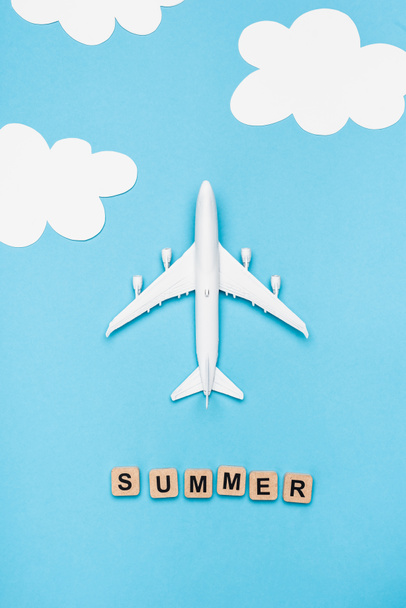 bovenaanzicht van vlak model en kubussen met woord zomer op blauwe lucht achtergrond - Foto, afbeelding