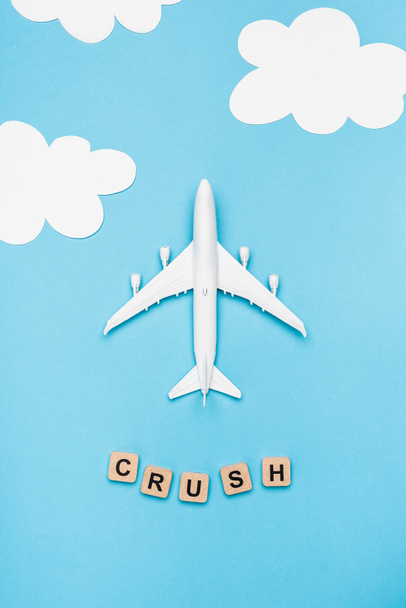 top view of plane model and cubes with word crush on blue sky background - Foto, afbeelding