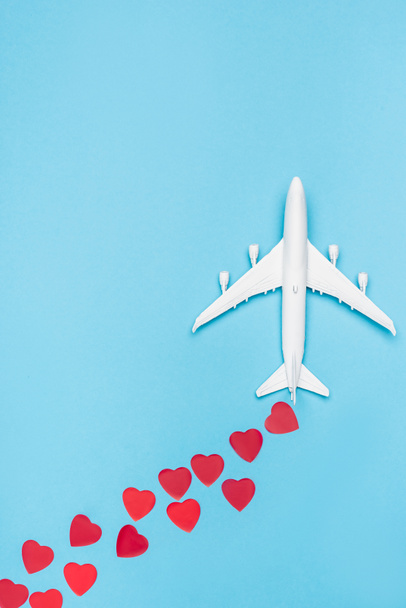 top view of plane model and red hearts on blue background - Фото, изображение