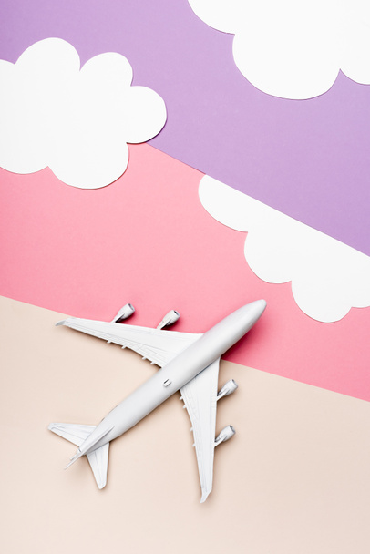 top view of white plane model on colorful background with clouds - Foto, Imagem