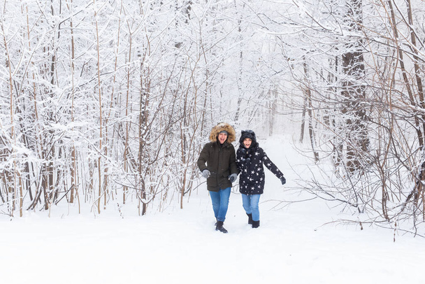 Happy couple walking through a snowy forest in winter - Photo, image