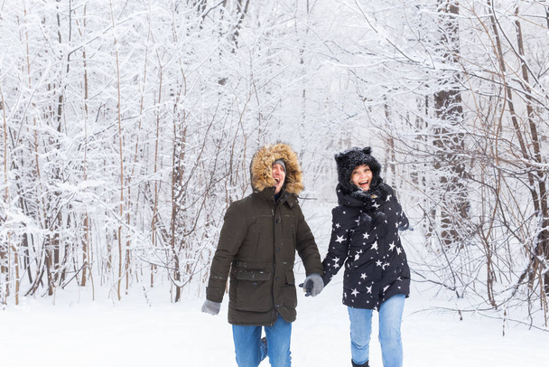 Boldog pár, akik télen egy havas erdőben sétálnak. - Fotó, kép