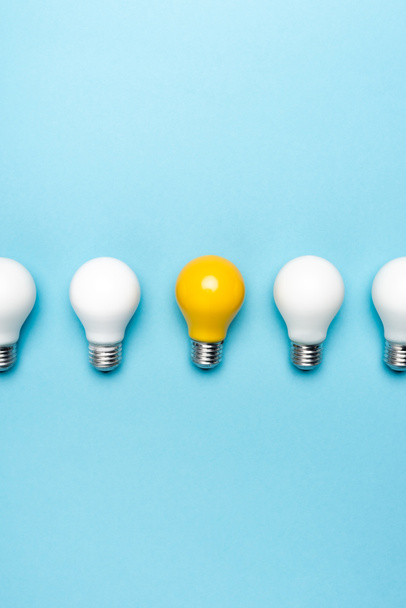top view of white and yellow light bulbs on blue background - Photo, Image